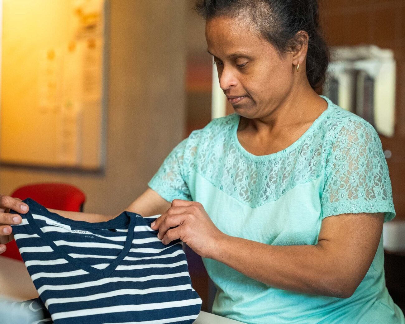 Eine Mitarbeitende der Wäscherei faltet ein T-Shirt