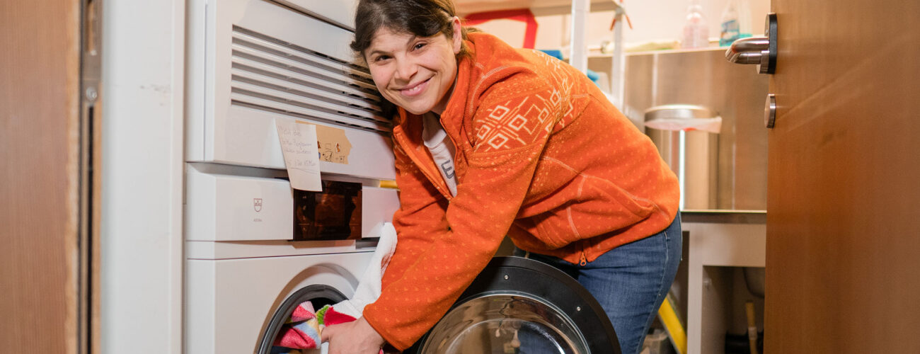 Eine Bewohnerin steckt die Wäsche in die Waschmaschine