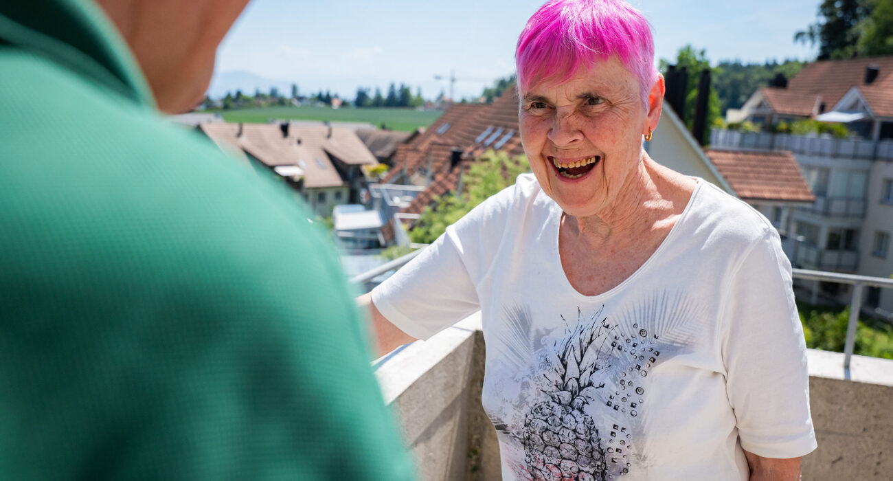 Eine Bewohnerin zeigt stolz die schöne Terrasse mit Aussicht